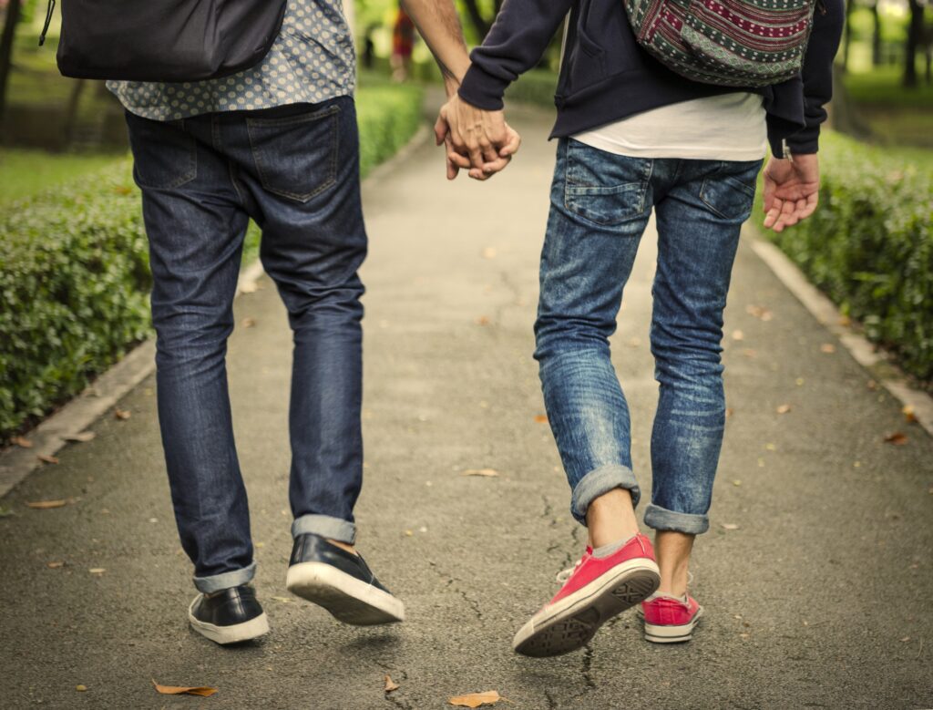 Imagen de dos chicos caminados mientras van tomados de la mano en un parque, disfrutando y viviendo de un amor consciente.