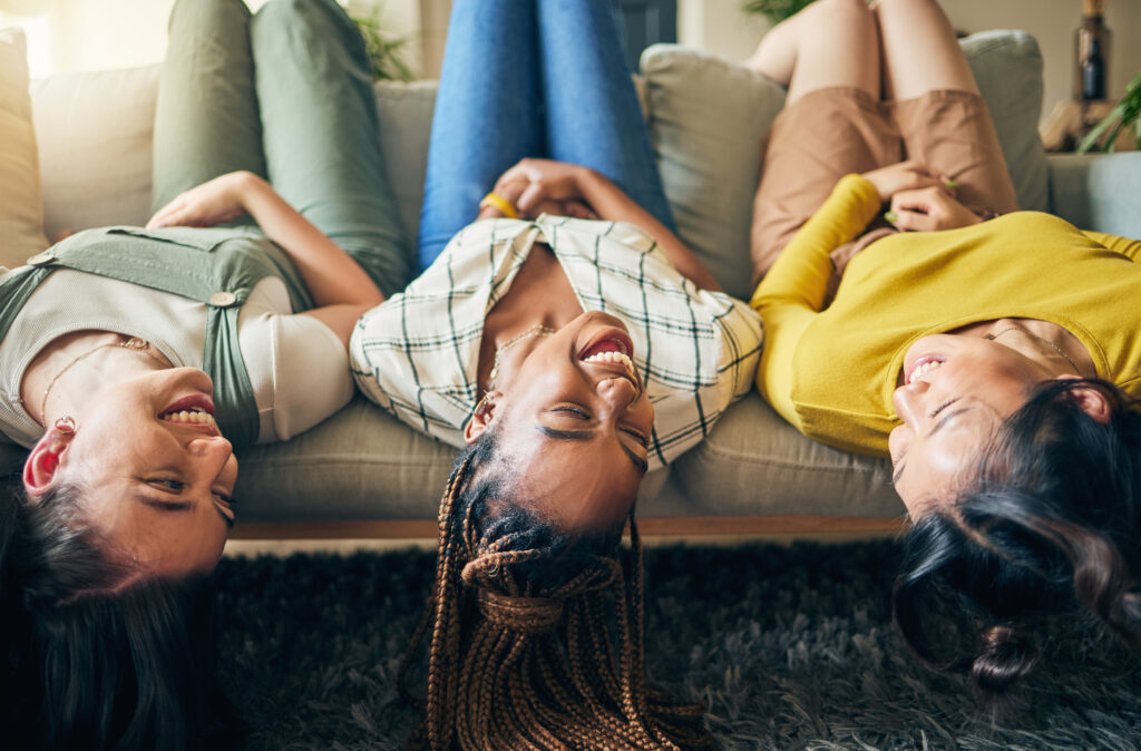 Tres jóvenes a costados en un sofá mientras cada uno disfruta de manera consciente el momento haciendo valer sus emociones a través de sus relaciones.