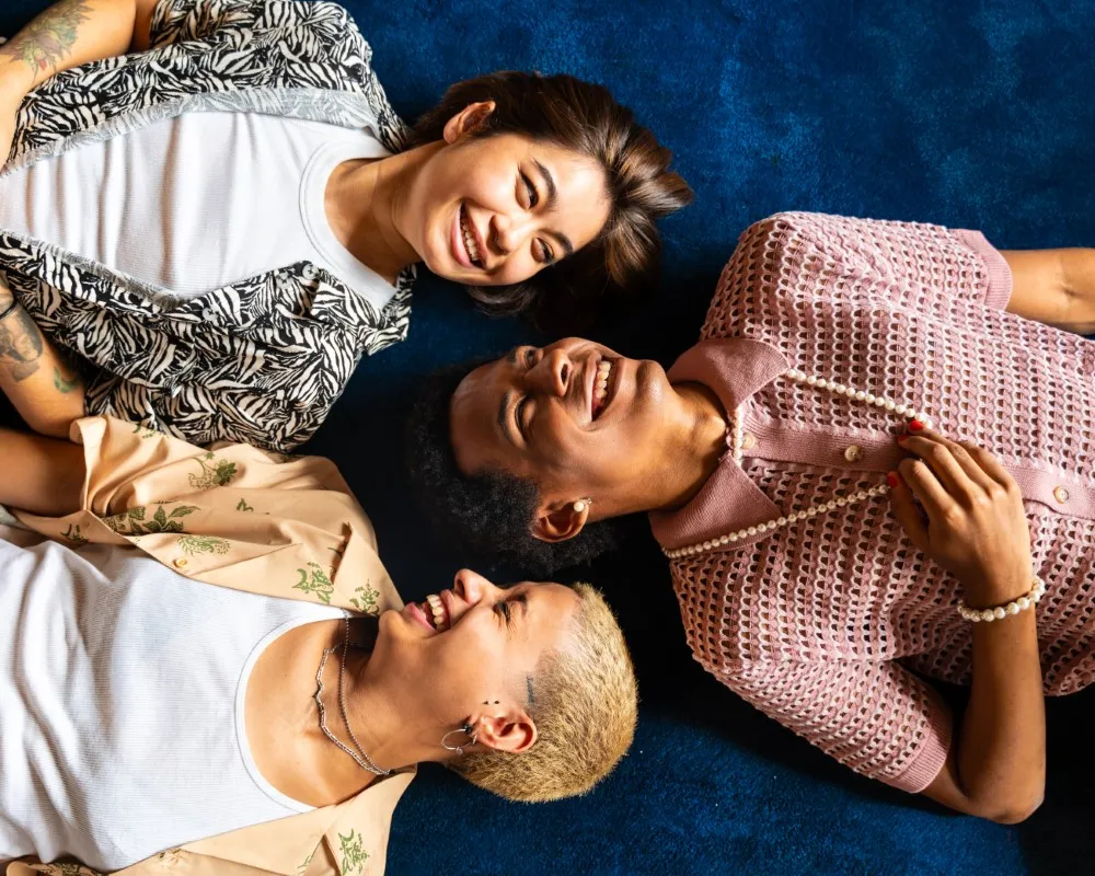 Se puede amar a más de una sola persona, hay tres personas que están acostadas en un piso que es azul