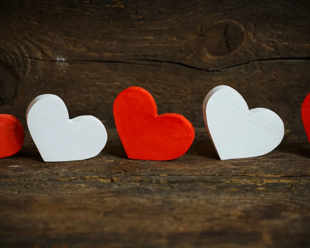 En una mesa de madera hay varios corazones que son blancos y rojos, hace referencia a ¿cómo saber si el amor libre para mí?