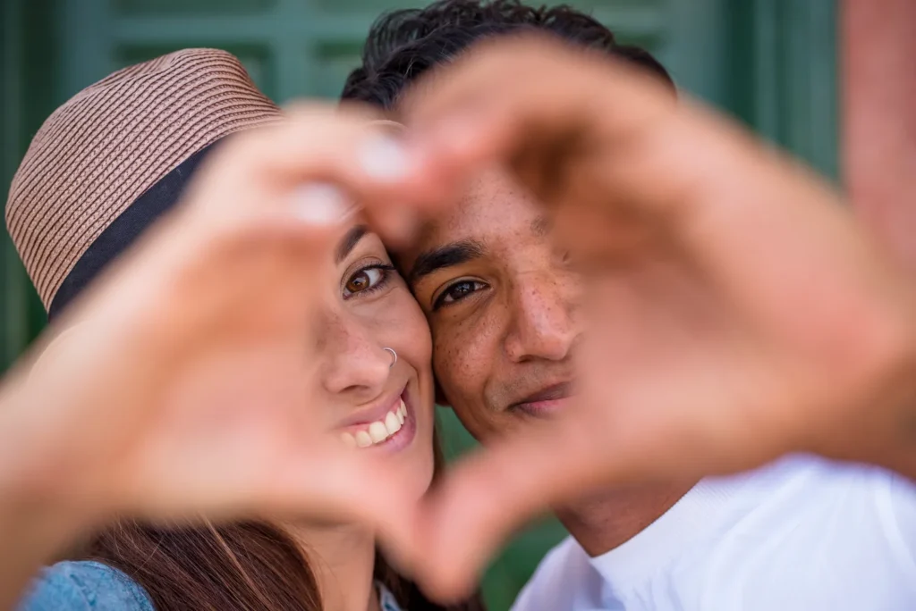 Hay dos personas que están haciendo un corazón con las manos, representan amor libre
