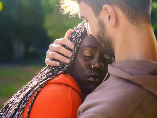 En el exterior hay dos personas que están abrazadas, representación de apego emocional